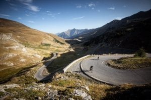 Riders tackling a bend in the mountains during the Route Des Grandes Alpes