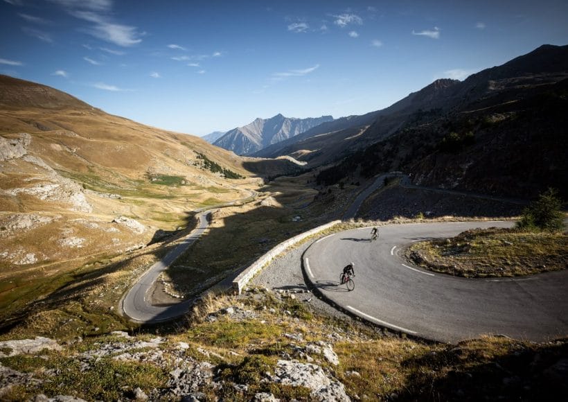 Riders tackling a bend in the mountains during the Route Des Grandes Alpes